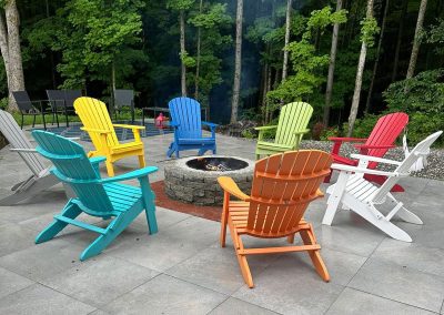 View of a Fire Pit Surrounded by Colorful Adirondack Chairs