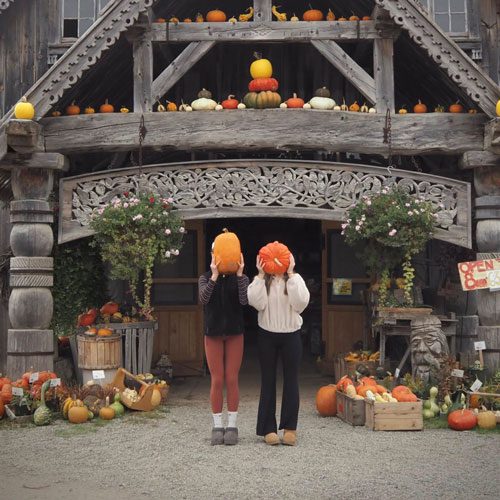 Two girls holding pumpkins in front of their heads