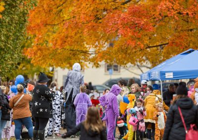 Large group of people in Halloween costumes in a park with fall leaves