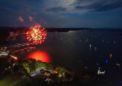Drone shot of red fireworks explosion over Lake Champlain with boats in the water