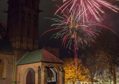 Large brick church with fireworks exploding in the sky behind it